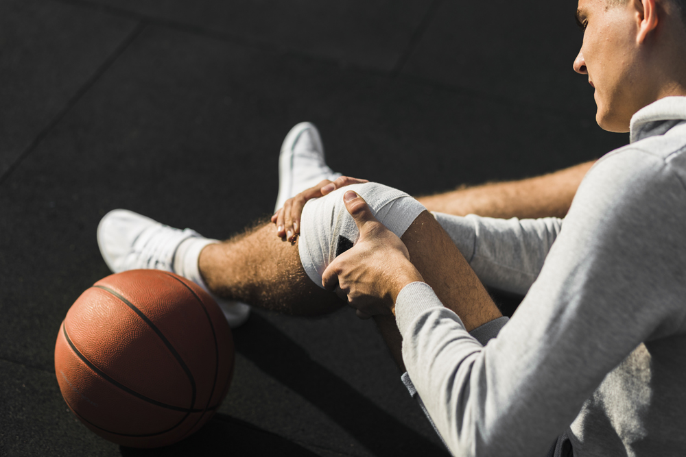 basketball-player-applying-bandage-knee